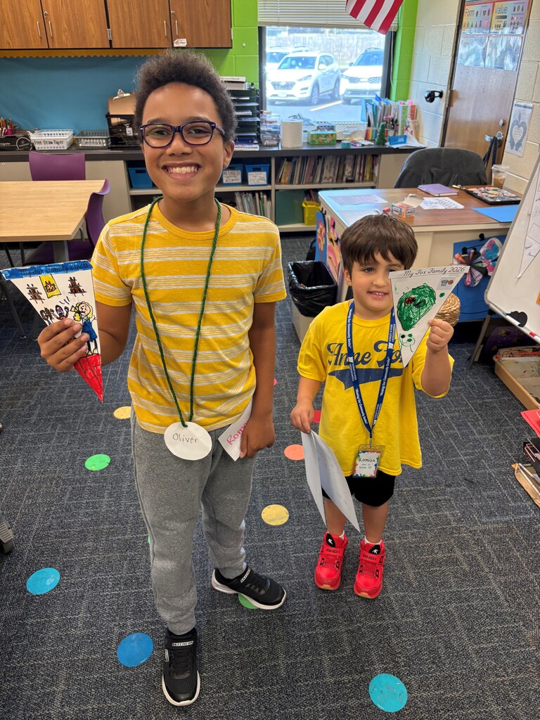 Two students holding their pennants they made with their fox families