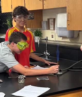 Students in Science class experimenting with Bunsen Burners and taking notes