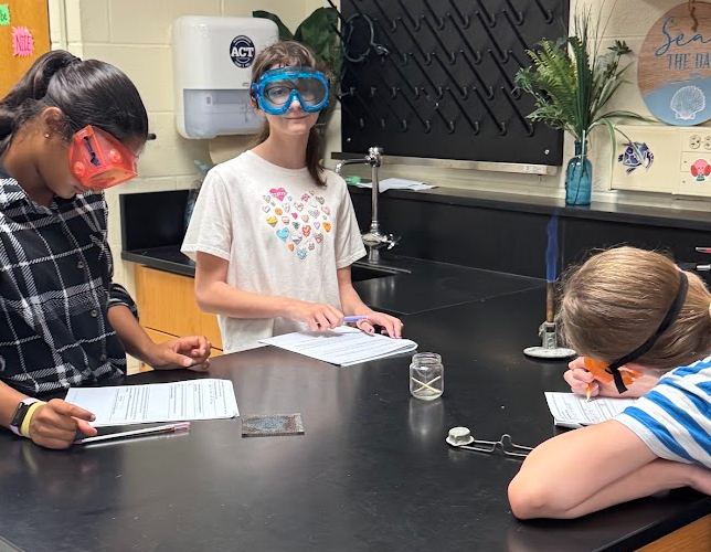 Students in Science class experimenting with Bunsen Burners and taking notes