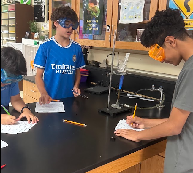 Students in Science class experimenting with Bunsen Burners and taking notes