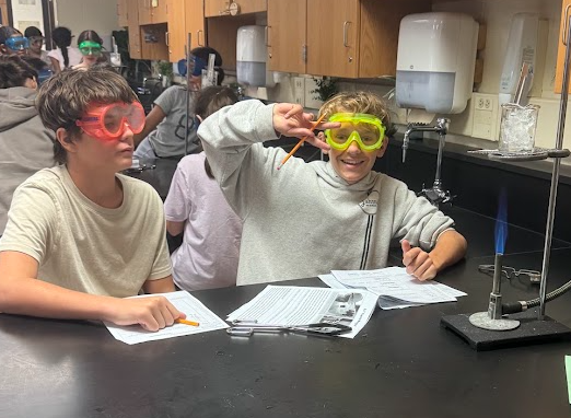 Students in Science class experimenting with Bunsen Burners and taking notes
