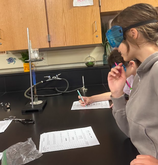 Students in Science class experimenting with Bunsen Burners and taking notes