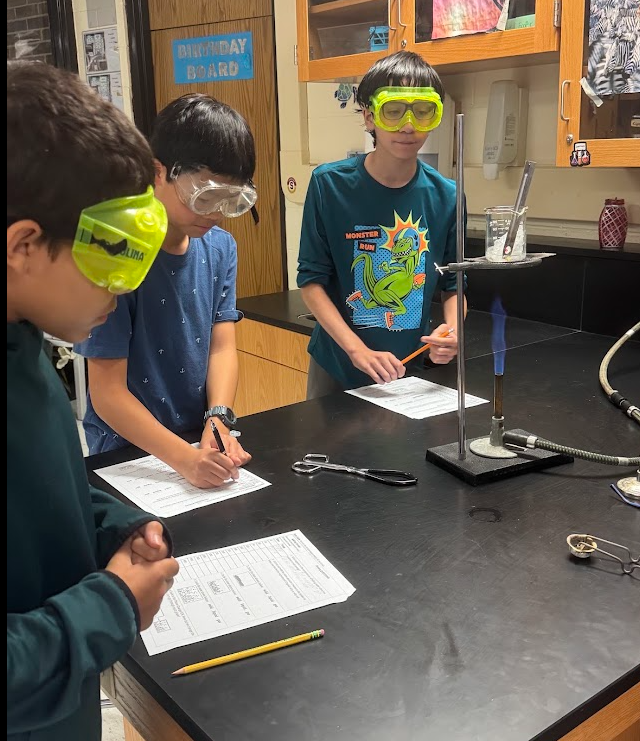 Students in Science class experimenting with Bunsen Burners and taking notes