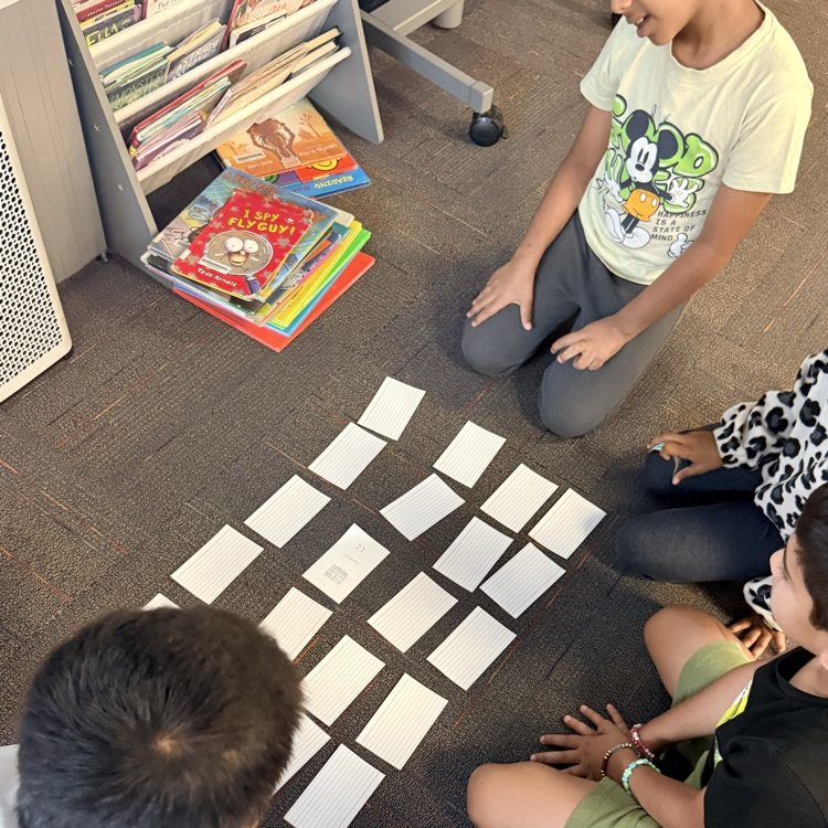 students looking at cards while playing a math game 