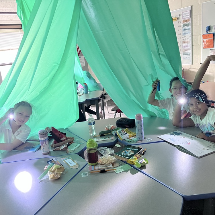 students with flashlights in their tents