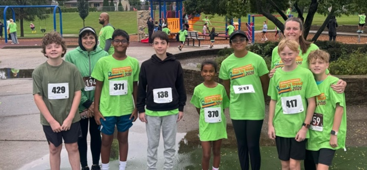 runners posing for a picture in front of a playground