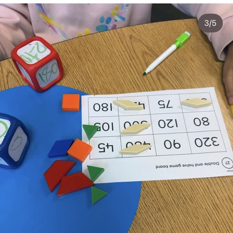 student working with dice and pattern blocks to mark numbers