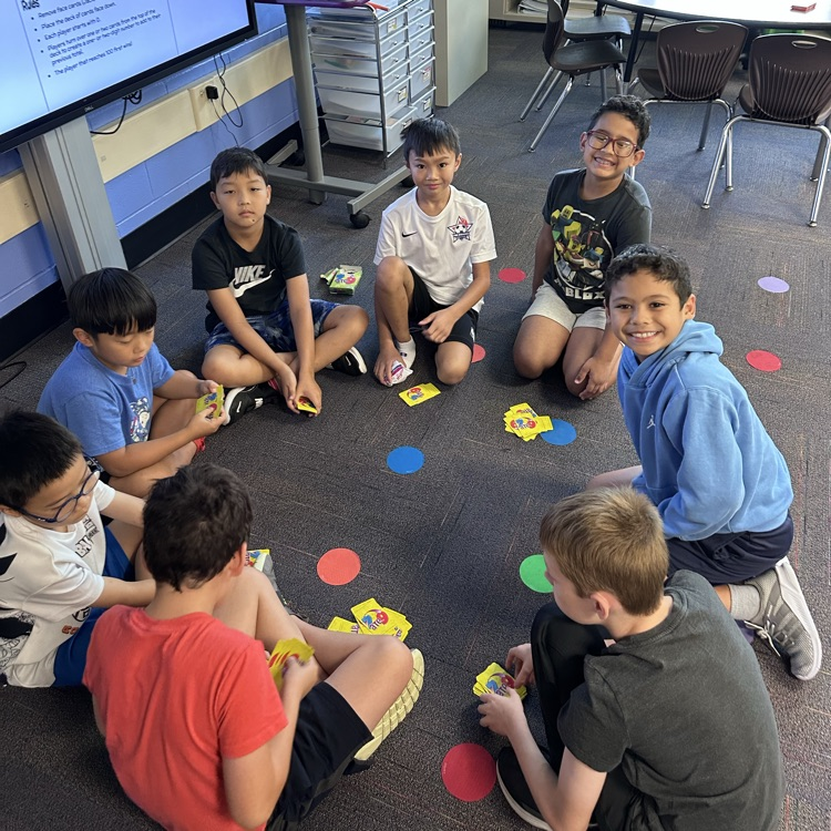 a group of students playing a card game on the floor 
