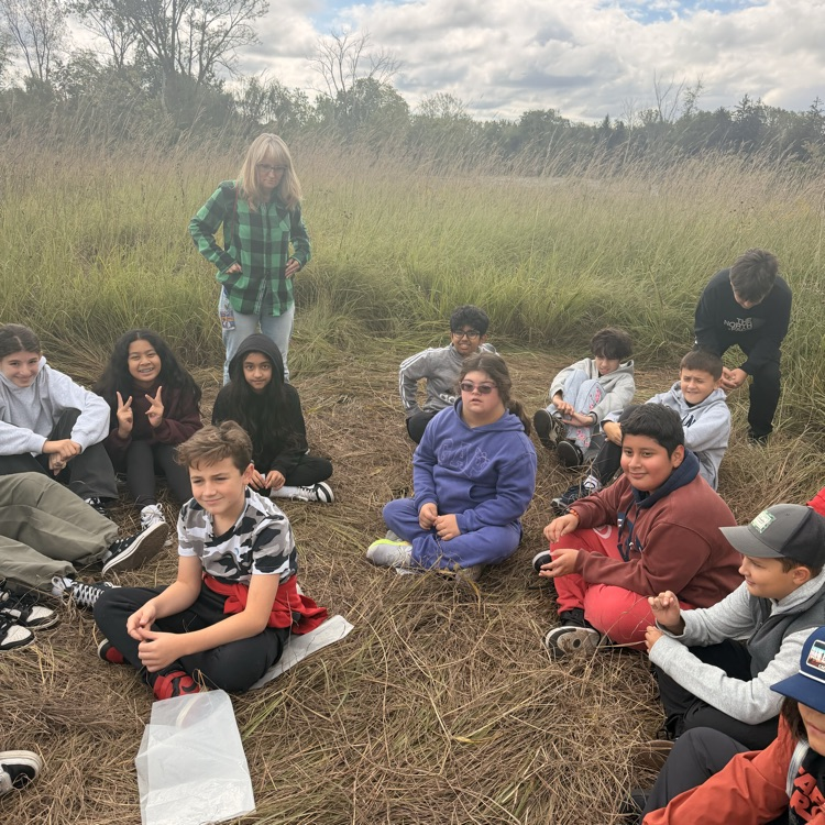students sitting in the middle of the field at Spring Valley listening to the guide