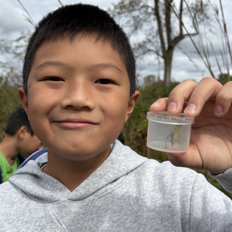 student showing a water sample he collected 