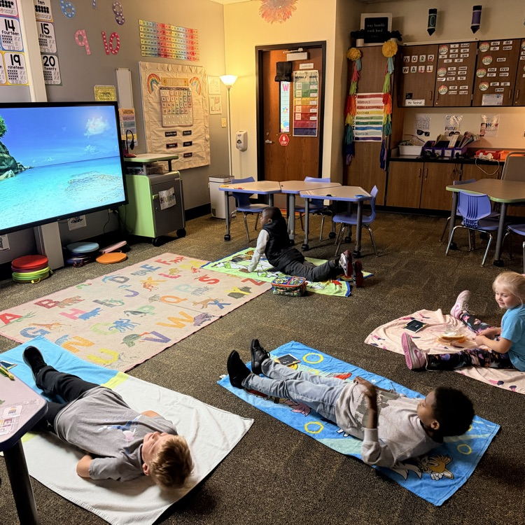 Students laying on beach towels with beach view on screen