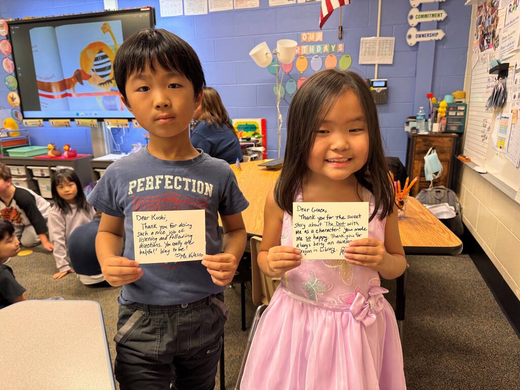 Two students holding postcards smiling
