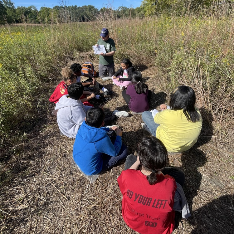 students sitting outside listing to an instructor