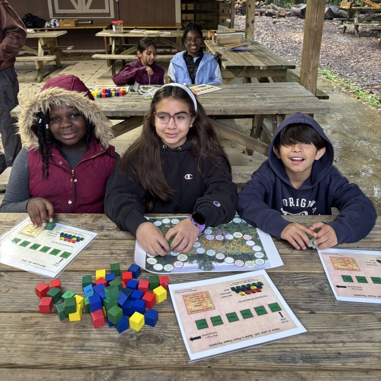 students sitting at picnic tables with learning materials