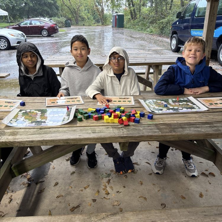 students sitting at picnic tables with learning tools