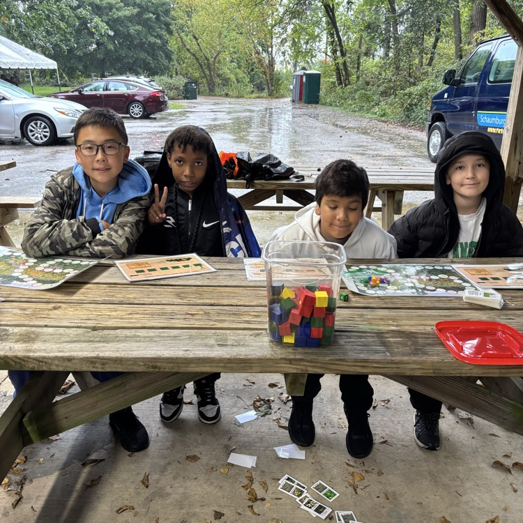 students sitting at picnic tables with learning tools