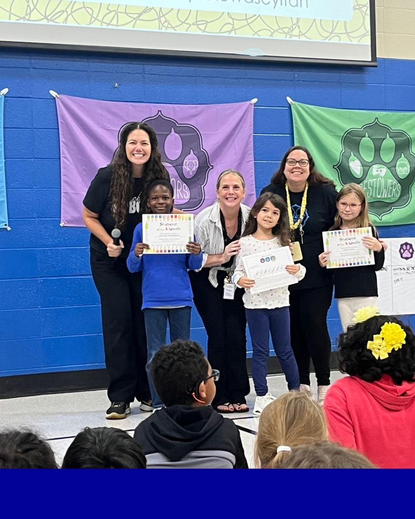 Students smiling with their award next to their teacher