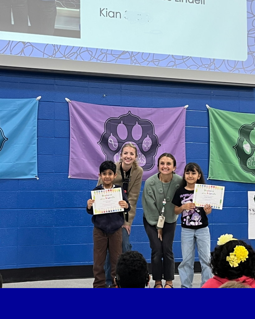 Students smiling with their award next to their teacher