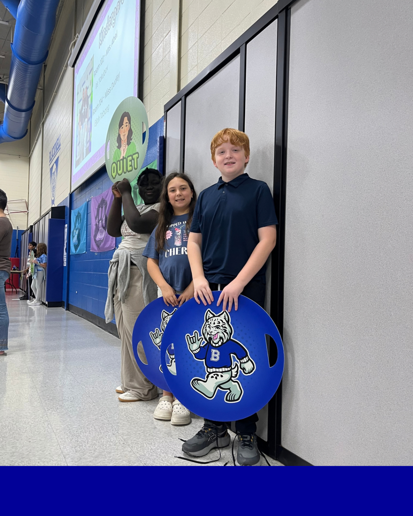 Students smiling holding Bobby the bobcat signs