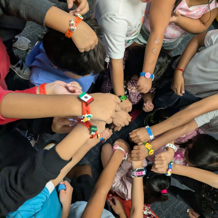 Students with bracelets they made and hands in the middle.