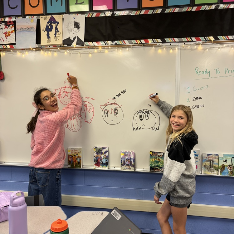 Two students using the white board during indoor recess.
