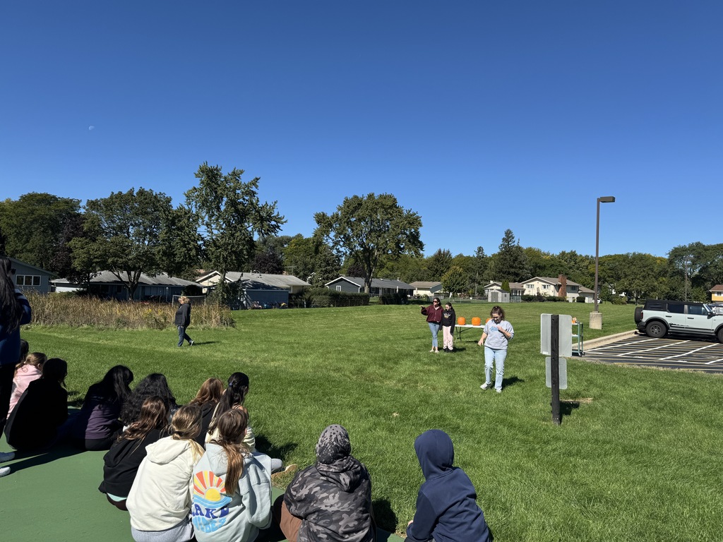 Students listen to a scientific demonstration of a self-carving pumpkin