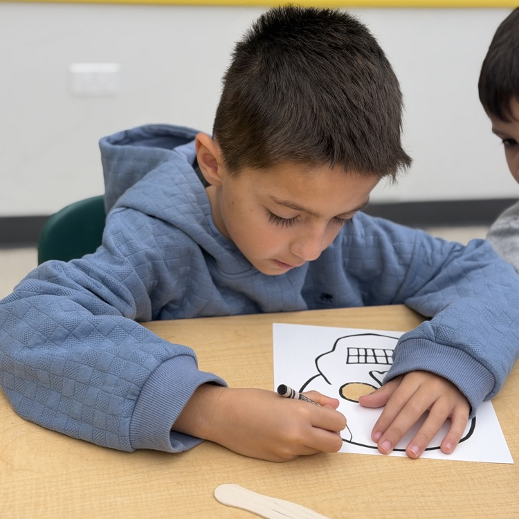 First grader decorating skull mask