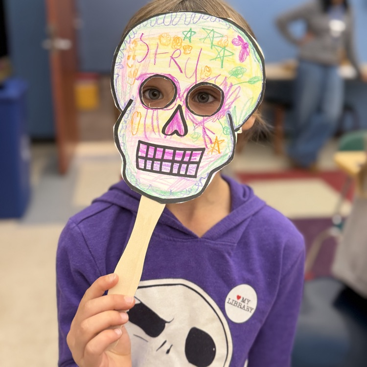 Student holding up skull mask