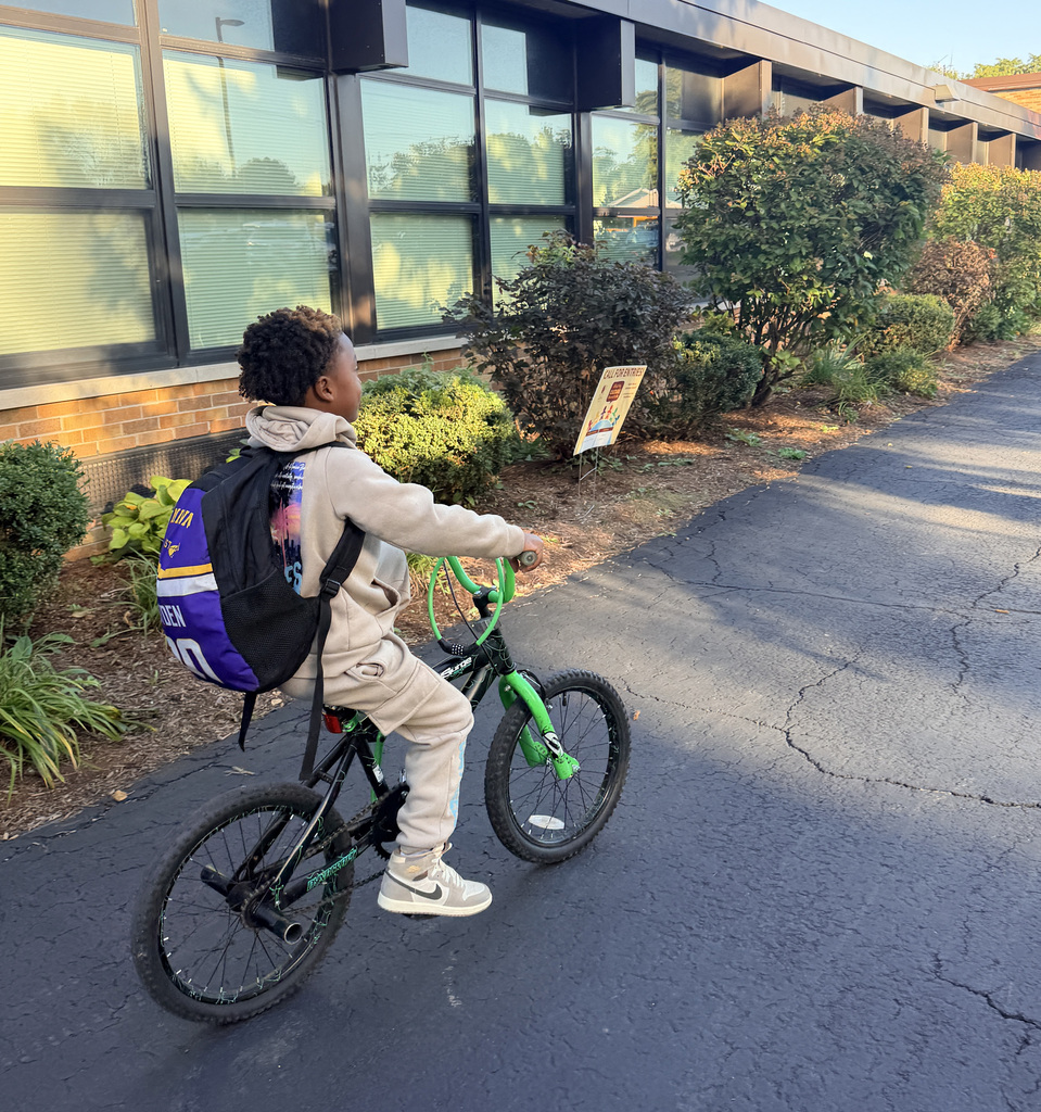 photo of a student riding his bike in front of Campanelli