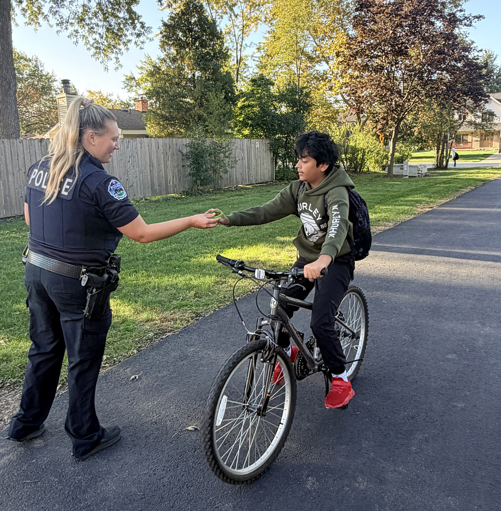 photo of student riding his bike and Officer Nowak giving him a bracelet