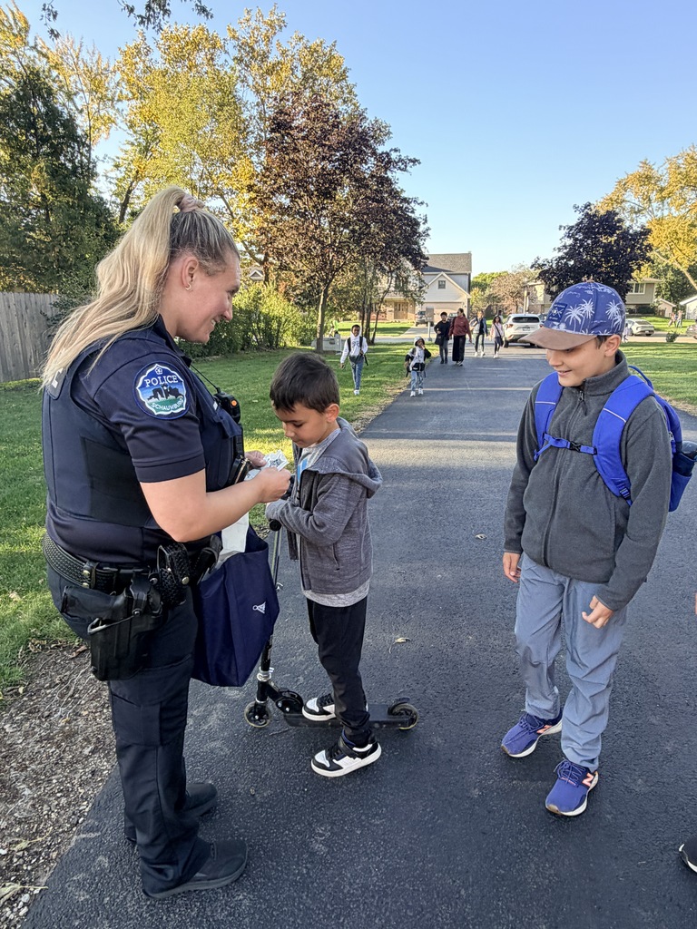 Office Nowak giving bracelets to two students who walked to school