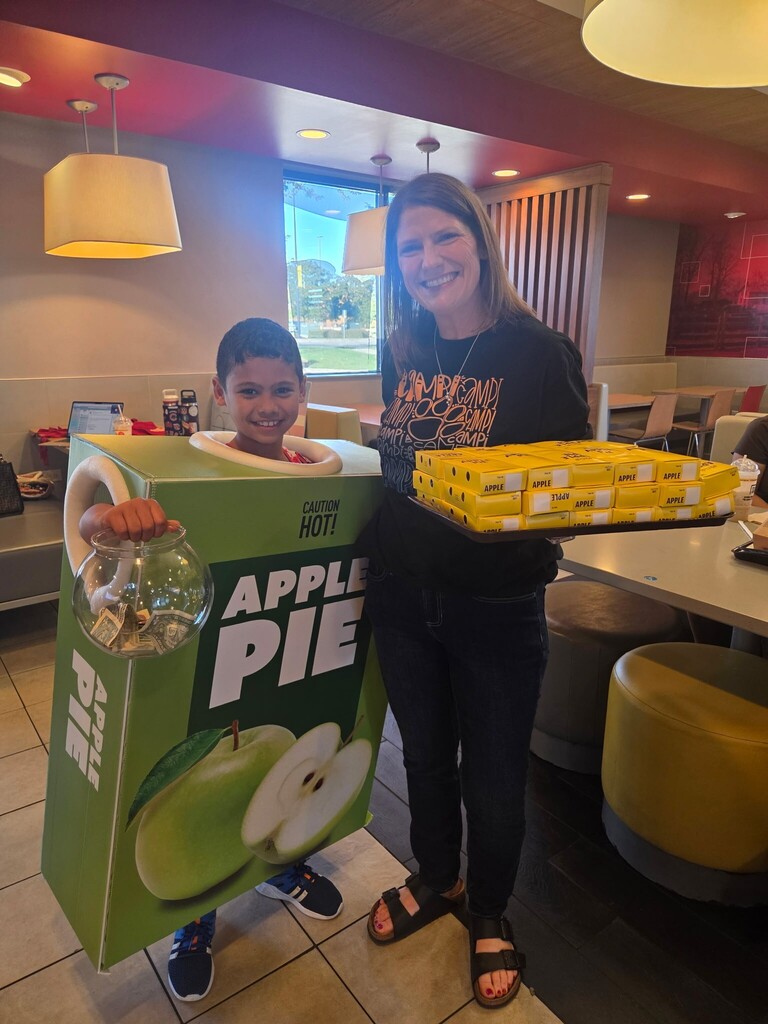 student in the McDonald's apple pie costume standing with a parent holding pies
