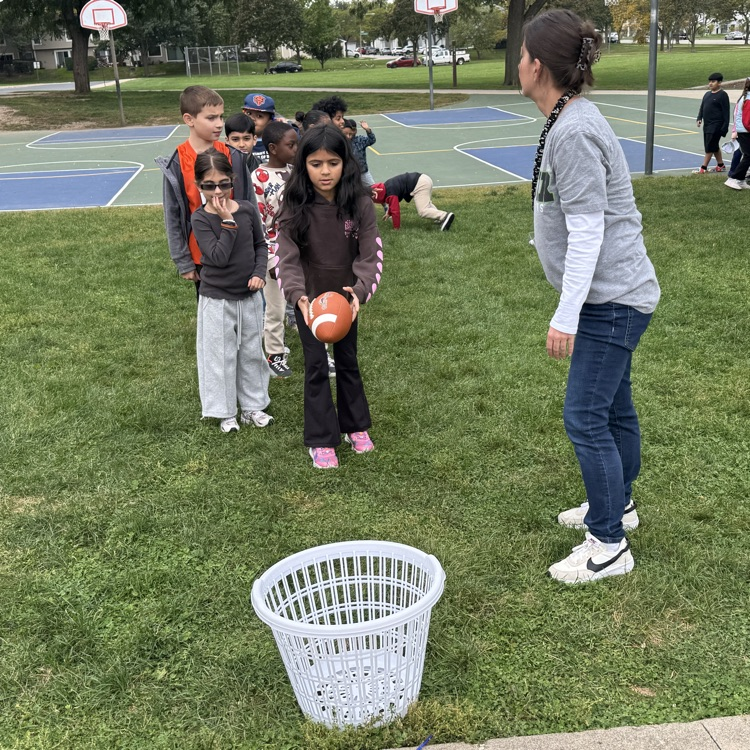 student throwing a football into a basket