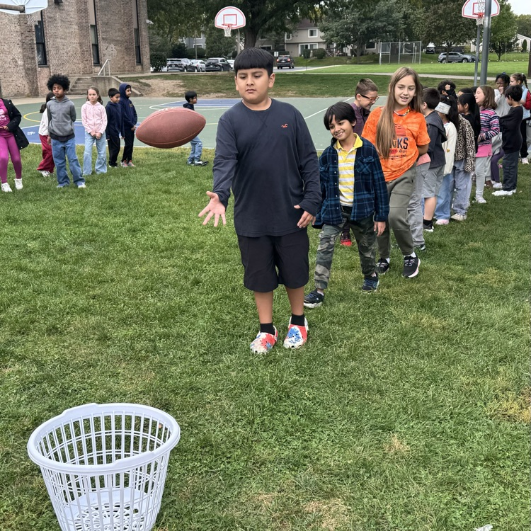 student throwing a football into a basket