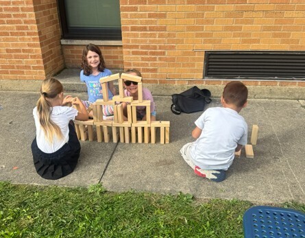 three students building with giant Jenga blocks