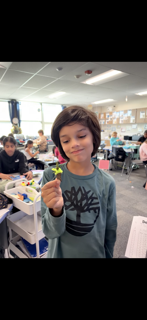 student holding a handmade tree craft