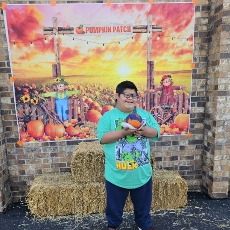 boy holding his painted pumpkin and smiling outside 