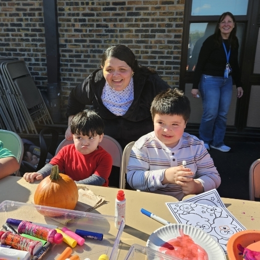 boy with his mom and little brother smiling and coloring