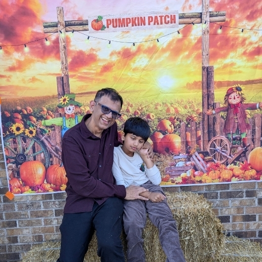 boy with his dad sitting on hay bales and smiling