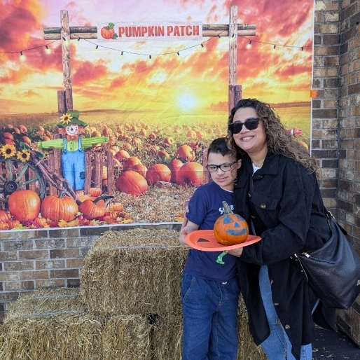 boy with his mom holding his painted pumpkin