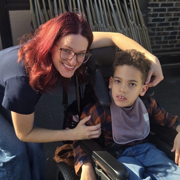 boy in a wheelchair with his mom smiling outside