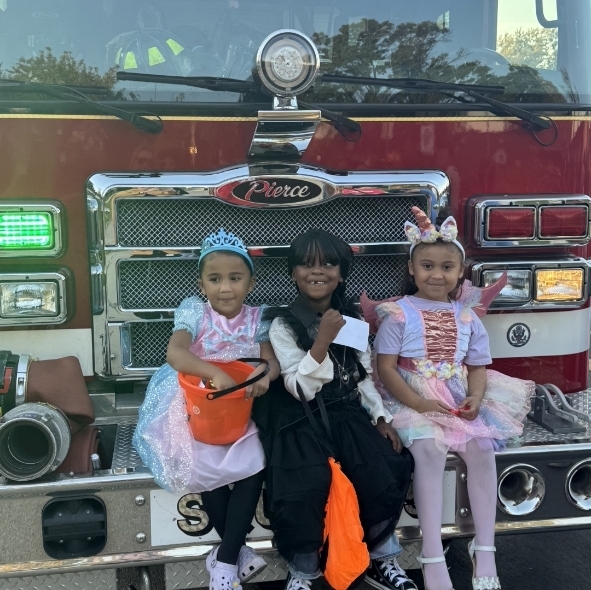 three girls sitting on a firetruck