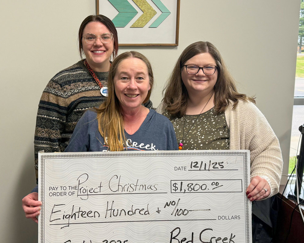 Three women posing with a large check for $1800 made out to Project Christmas.