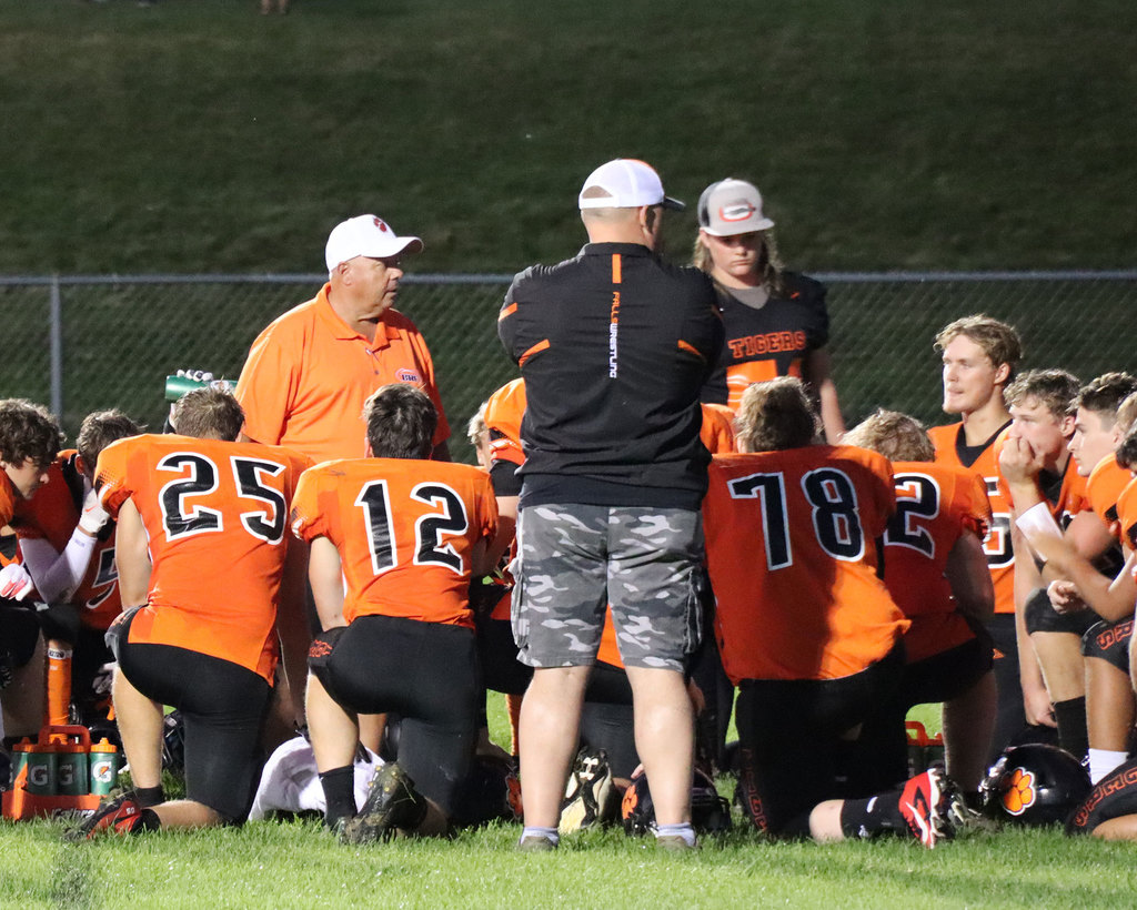 Football players kneeling and listening to coach.