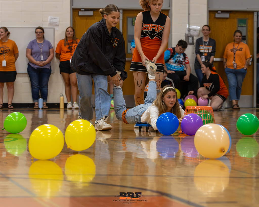 Student scoots on the floor and tries to capture balloons.