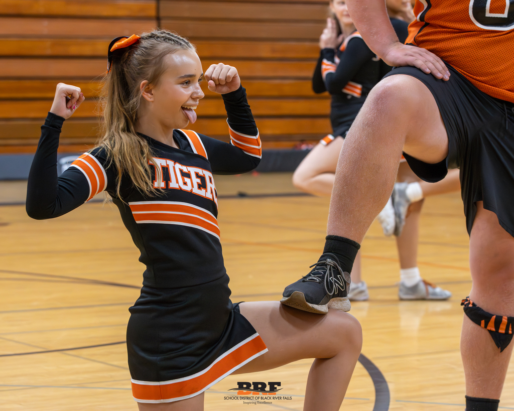 Cheerleader kneeling on floor, partner's shoe on her knee