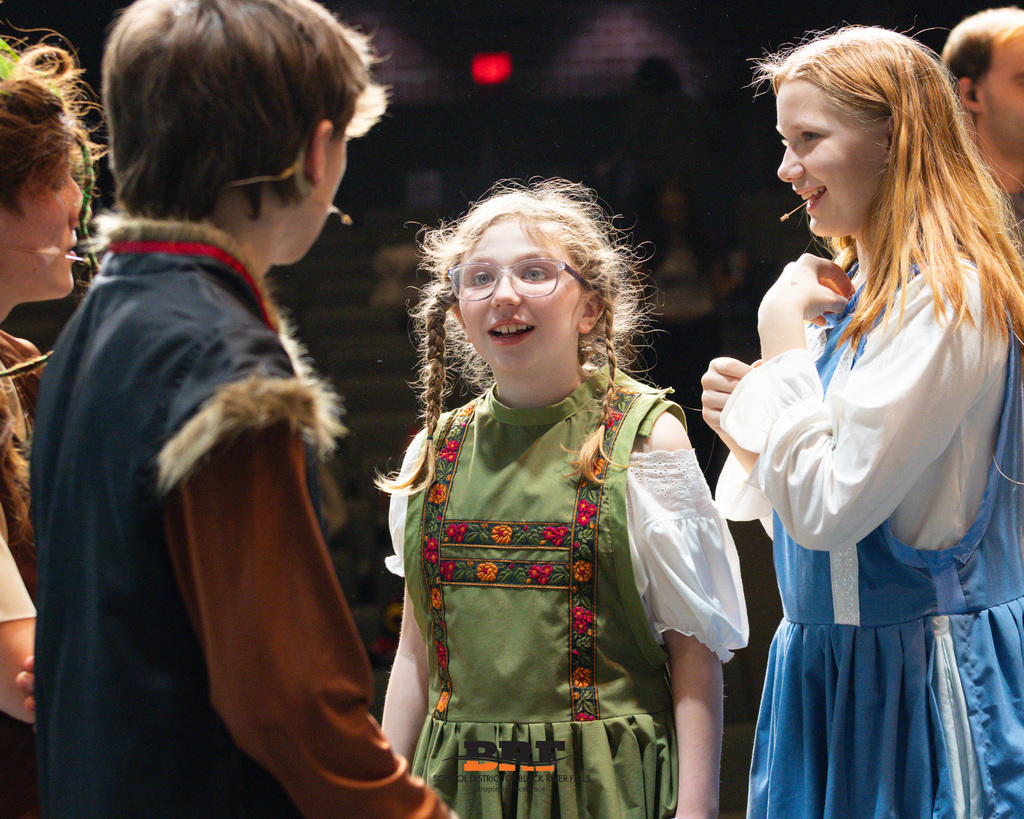 Girl looks at castmate on stage.