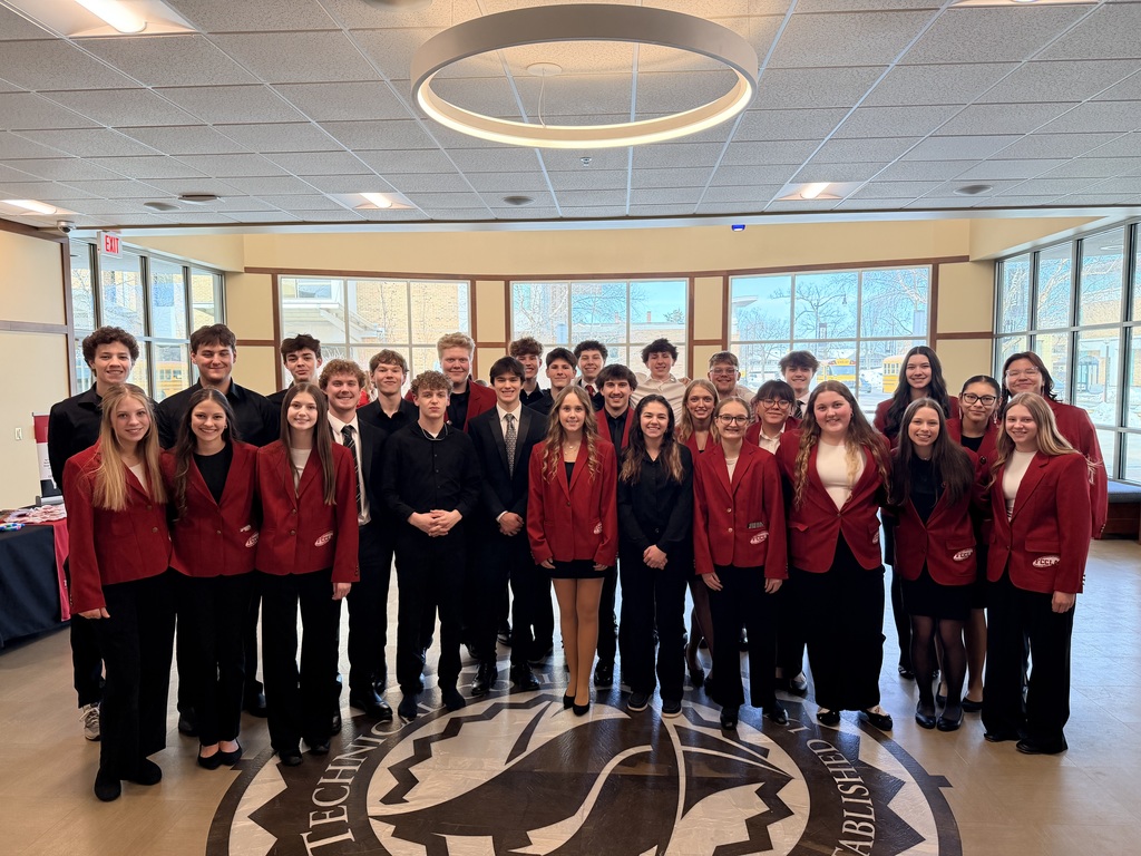 Students wearing red blazers stand in two rows, looking at the camera.
