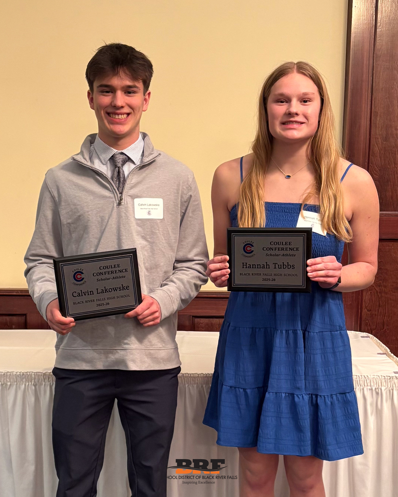 Two people smiling at camera, holding plaques.
