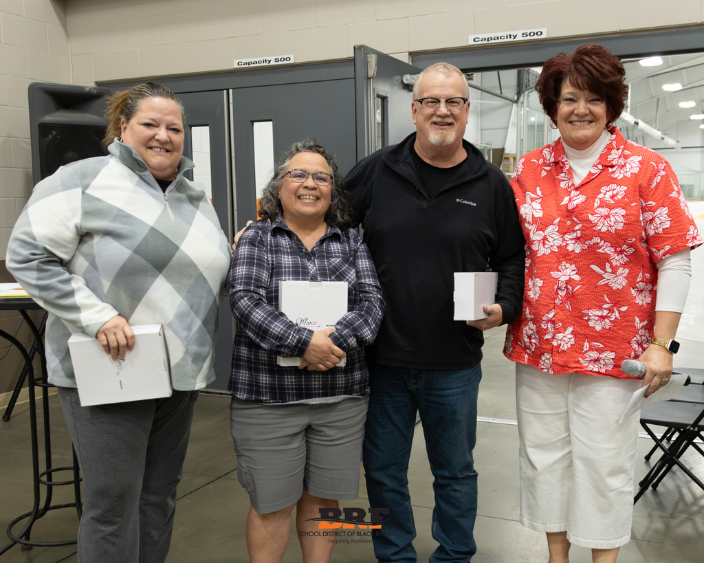 Photo of four staff members smiling and posing in a row.